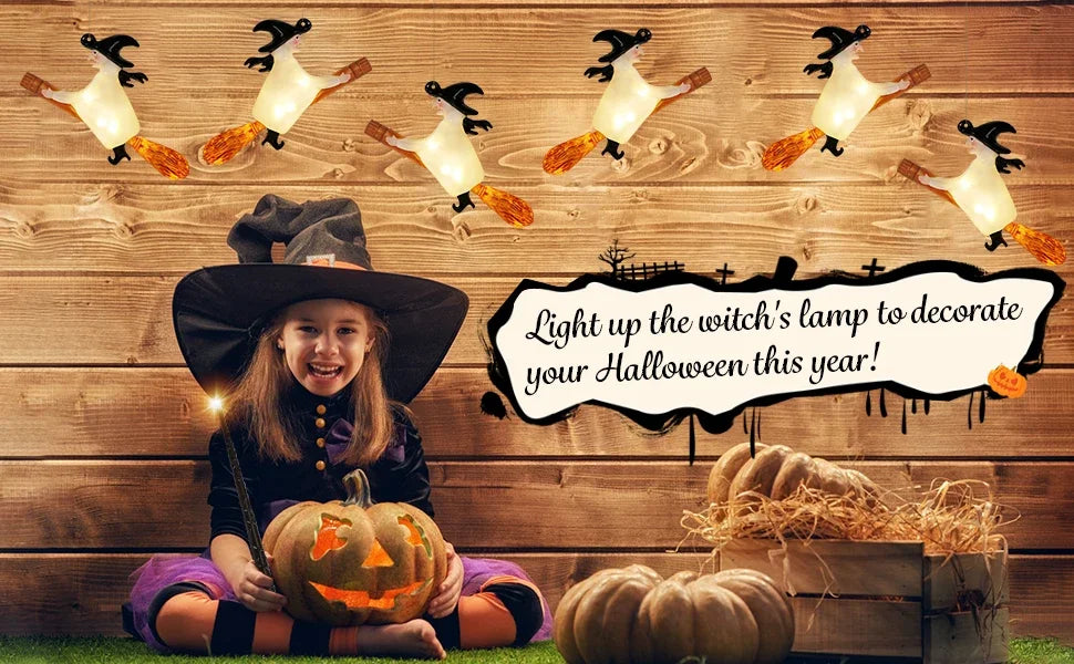 A young girl in a witch costume sits in front of a wooden background decorated with floating LED candles and pumpkins for Hal