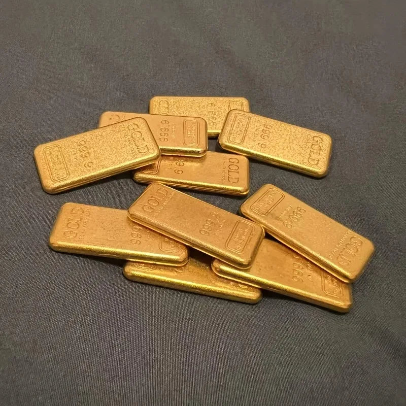 A collection of ten rectangular simulated gold ingots or fortune charms arranged on a dark gray surface.