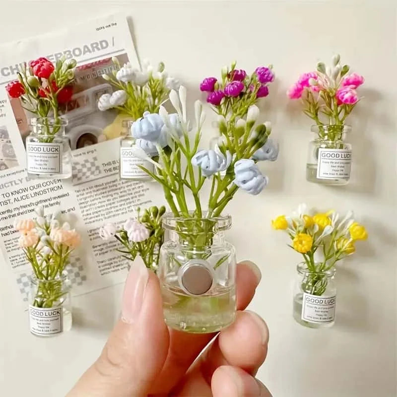 A hand holds several glass jars filled with colorful dried flowers used as decoration.
