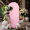 A pink arch backdrop decorated with white flowers and gold balloons for an event display.