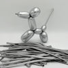 A silver latex modeling balloon shaped like a dog stands next to a pile of thin, metallic rods.