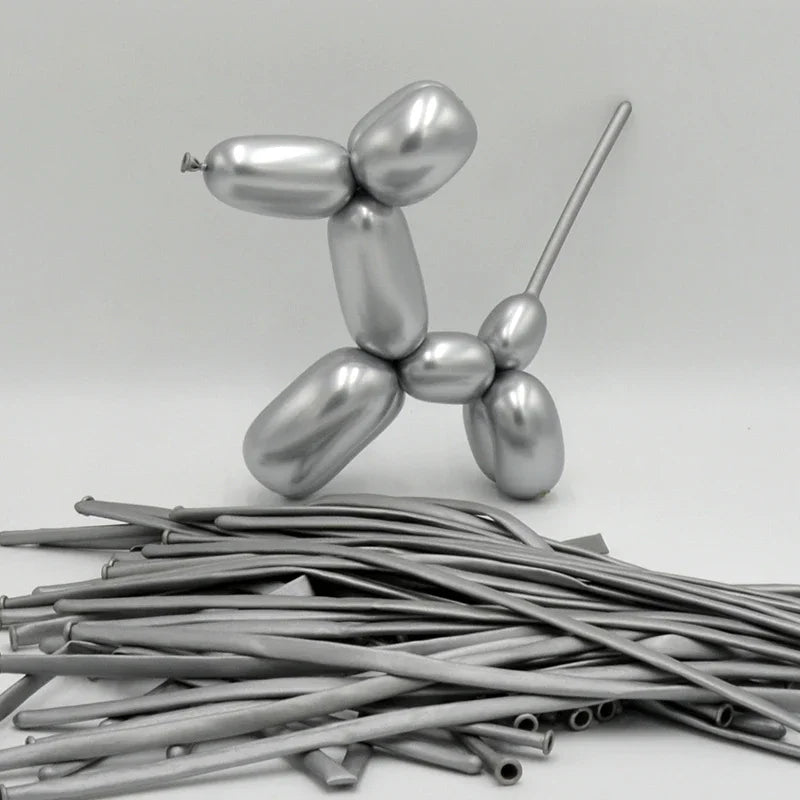 A silver latex modeling balloon shaped like a dog stands next to a pile of thin, metallic rods.