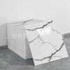 A stack of white faux marble tiles with gray veining is displayed next to a single tile.
