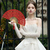 A woman models a vintage red lace hand fan with a tassel pendant and a white dress.