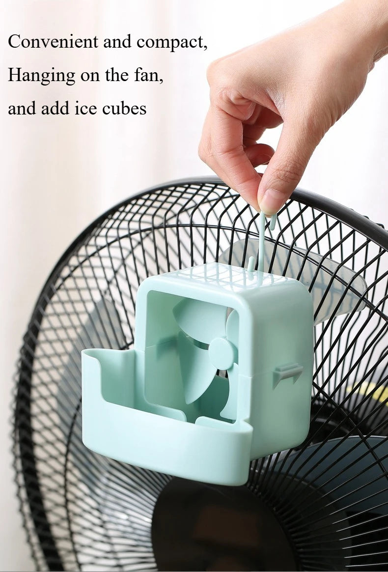A hand is hanging an ice cube into the housing of a portable ice-cooling floor fan.