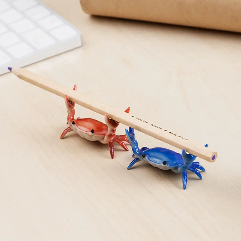 A wooden stick shaped like a crab is used as a desk organizer for holding a pen and phone.