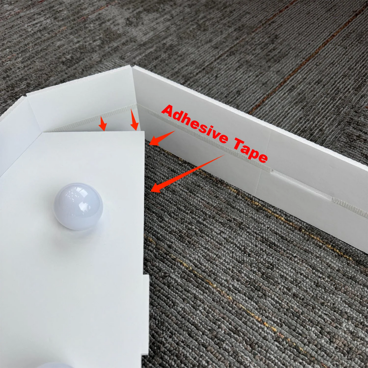 A white marquee number sign with a spherical light, showing adhesive tape for mounting on a gray fabric background.