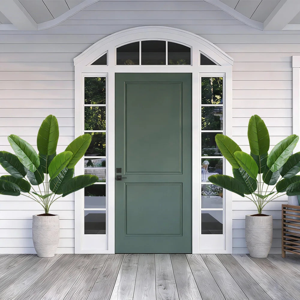 A green door with glass panels is set into a white wooden door frame flanked by large artificial palm trees.