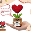 A handcrafted crochet heart plant with a small wooden pot and a note, held in a person's hand.