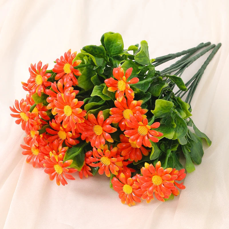 A bouquet of lifelike silk orange and yellow daisies with green leaves.