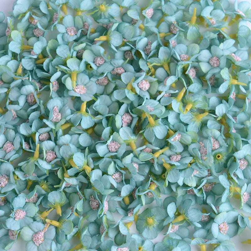 A close-up of a set of 50 light blue silk artificial flower heads with yellow stamens and pink accents.