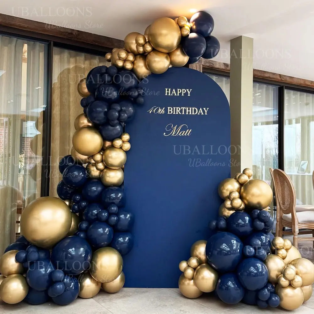 A balloon garland featuring metallic gold and navy blue balloons decorating a backdrop for a birthday party.