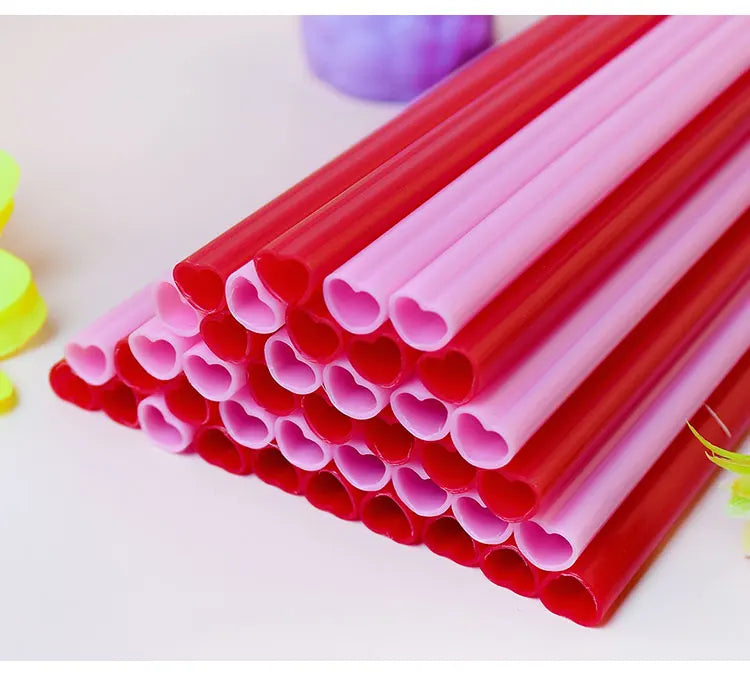A close-up view of a large pack of heart-shaped pink disposable straws in red and pink colors.