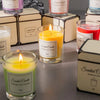 A collection of scented candles in glass jars and boxes with yellow, pink, and red wax.