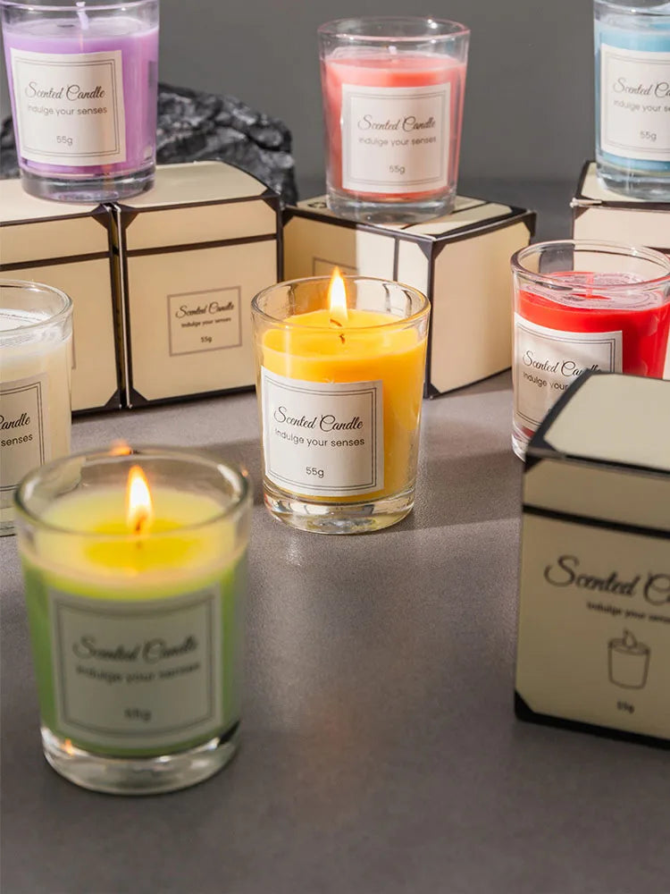 A collection of scented candles in glass jars and boxes with yellow, pink, and red wax.