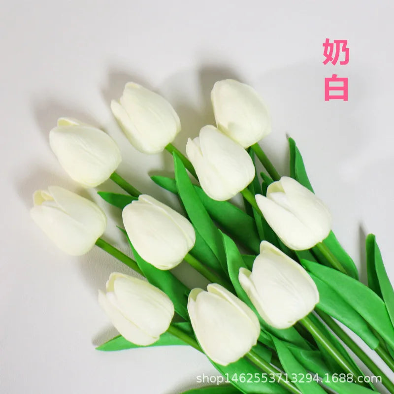 A bouquet of six white artificial tulips with green stems and leaves.