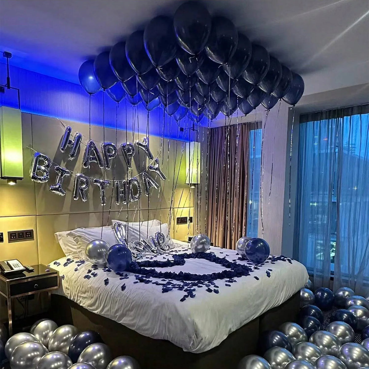 Ein Bett dekoriert mit blauen Ballons und einem großen Ballonbogen in einem Raum.