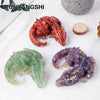 A display of natural crystal dragon figurines, including a red and a purple specimen, set against a white background.
