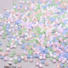 A pile of faceted bicone glass beads in mixed pastel colors including pink, green, and blue.