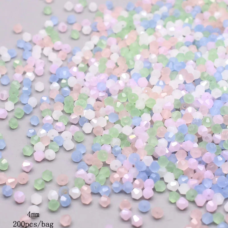 A pile of faceted bicone glass beads in mixed pastel colors including pink, green, and blue.