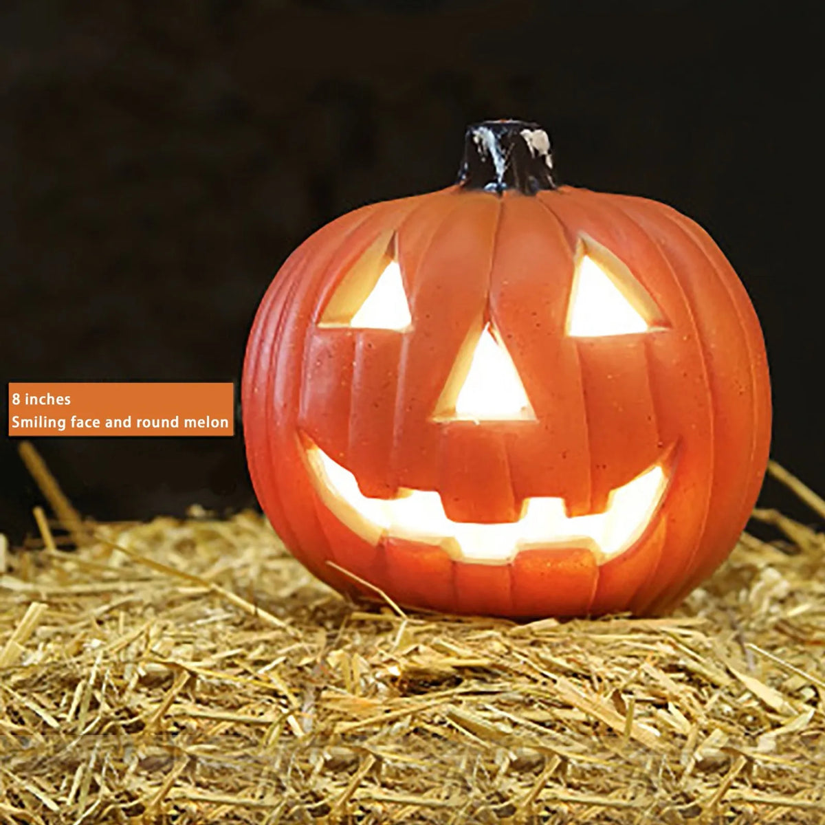 Linterna de calabaza de cerámica naranja con cara sonriente, colocada sobre paja.