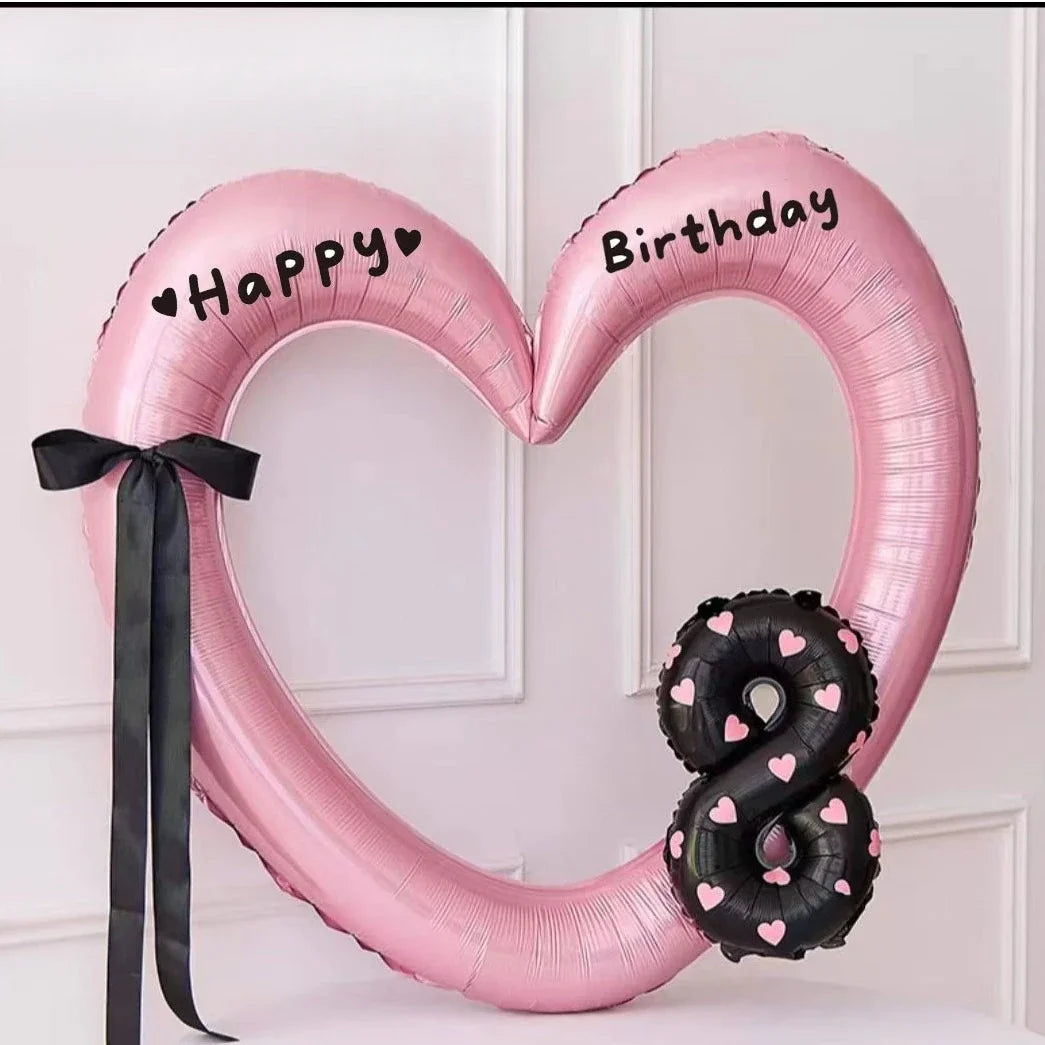 Pink heart-shaped balloon decoration with Happy and Birthday text and a black snake balloon