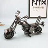 A silver-toned retro iron motorcycle figurine displayed on a light surface.