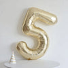 A large gold foil number balloon shaped like the number 5 is displayed against a white background.