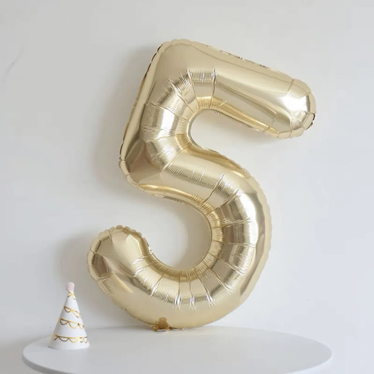 A large gold foil number balloon shaped like the number 5 is displayed against a white background.