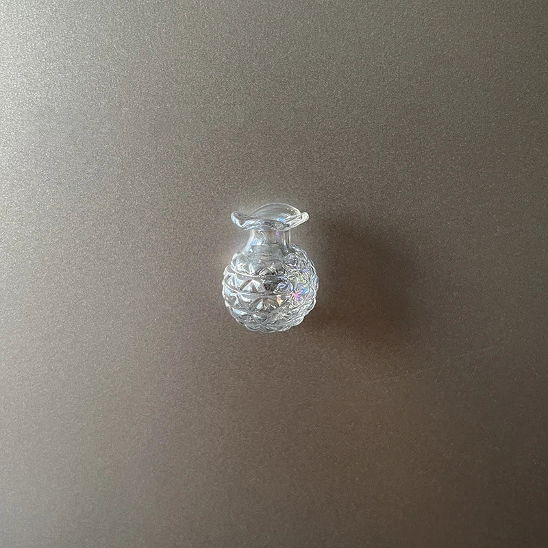 A clear glass decorative item with a rounded body and a small stopper, displayed against a neutral background.