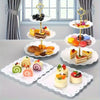 A set of decorative white food trays and stands displaying various small desserts and pastries.