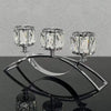 Three-arm gold crystal candelabra with three glass candle holders displayed on a reflective surface.