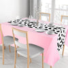 A pink cow print western tablecloth set for parties featuring a table, plates, and silverware.