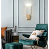 Modern bubble crystal LED wall sconces mounted on a light gray wall above a dark green velvet chair.
