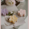 A collection of handmade soy wax flower tea light candles in various pastel colors, set against a soft background.