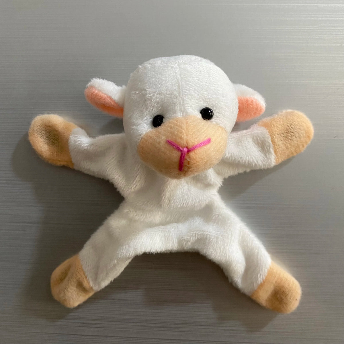 A white plush toy resembling a baby elephant with pink accents and floppy ears.