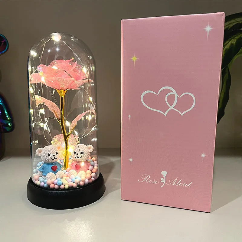 Flor de rosa de plástico luminosa, cubierta decorativa, junto a su caja rosa con diseño de corazón.