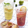 Two plastic cups filled with iced tea or juice garnished with citrus slices on a checkered cloth.