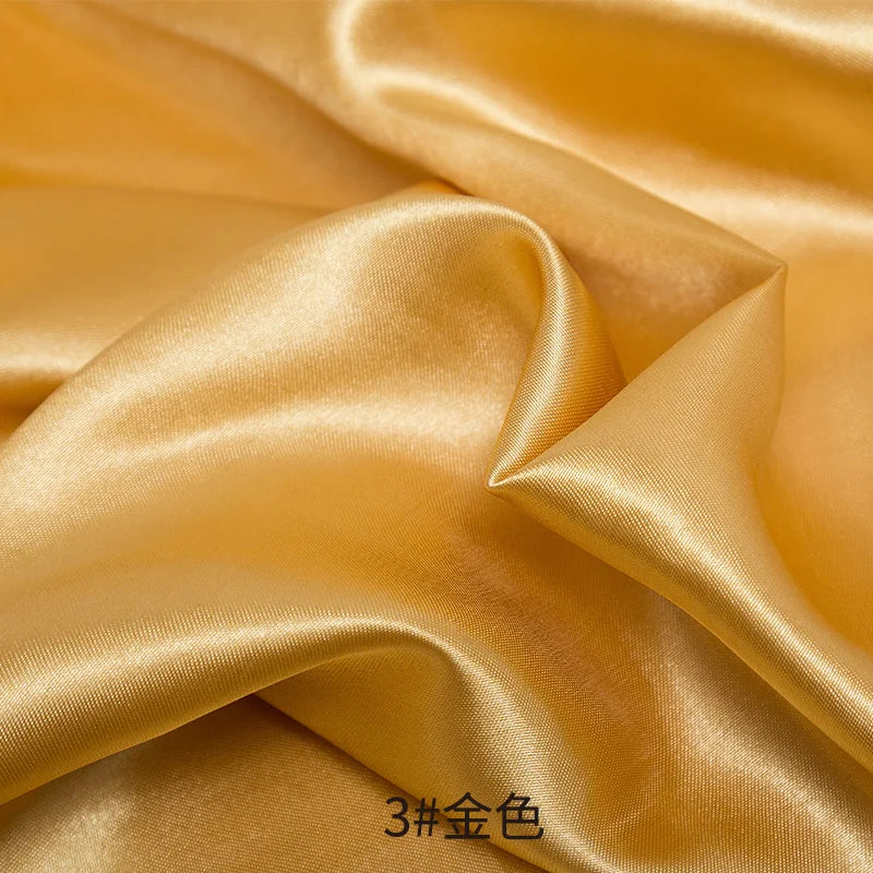 Golden satin fabric draped and folded showing luxurious texture for sewing projects