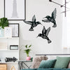 Black silhouette of three hummingbirds in flight on a white wall