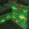 Glow-in-the-dark dinosaur wall stickers illuminating a wooden shelf in a room.