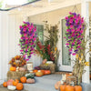 A vibrant purple and pink artificial morning glory and eucalyptus garland decorating a porch entrance with pumpkins.
