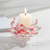A clear glass lotus-shaped candle holder with a white candle and flame on a reflective surface.