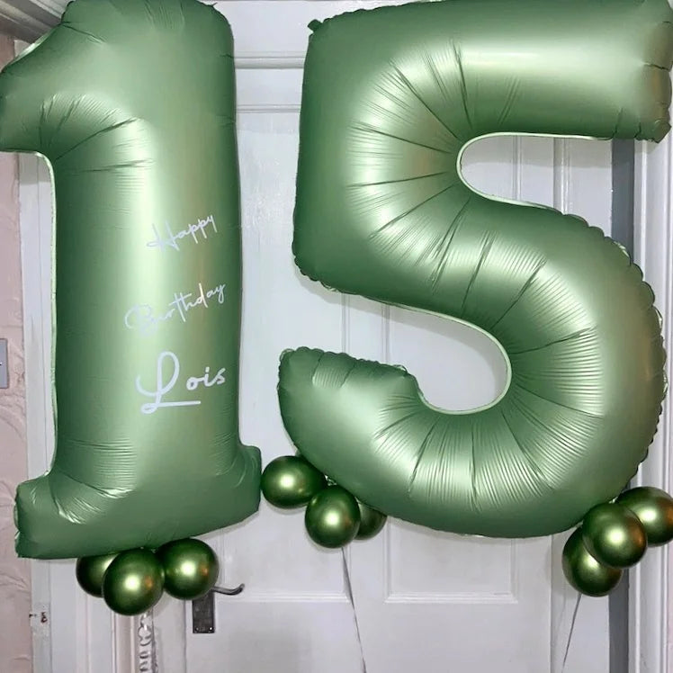 A set of foil balloons shaped like the numbers one and five in a muted olive green color for birthday decoration.