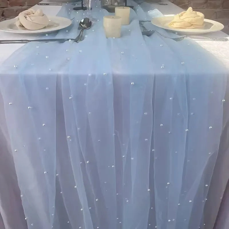 A light blue sheer fabric table flag decorated with scattered beads and used as a table runner.