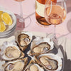 A still life featuring a glass of rosé wine, lemons, and several oyster shells on a plate.