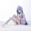 A figurine of an anime girl with long blue hair sitting in the snow.