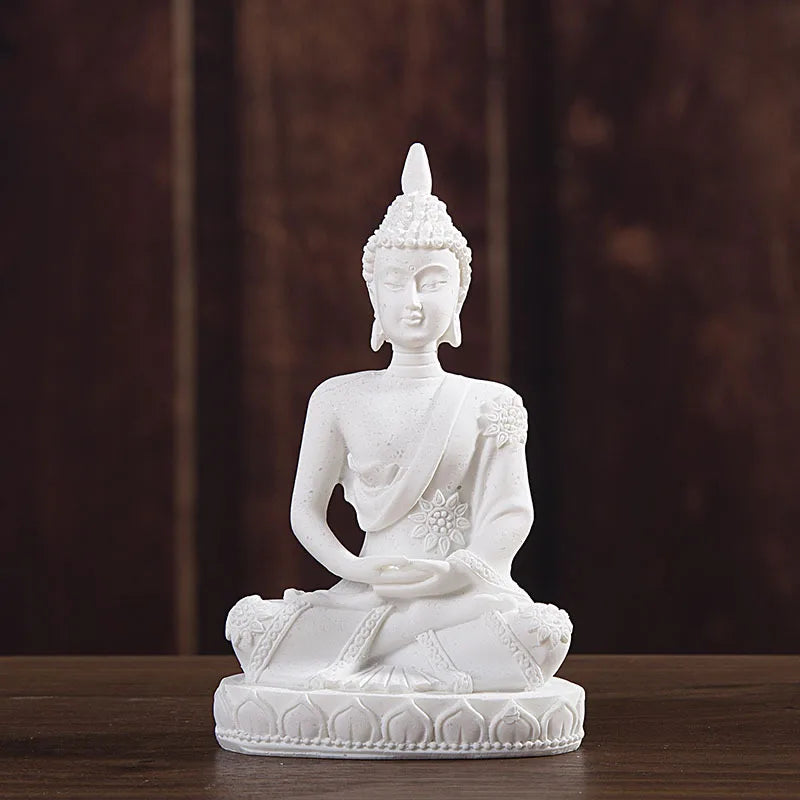 White handcrafted resin Buddha statue seated in meditation on a wooden surface.