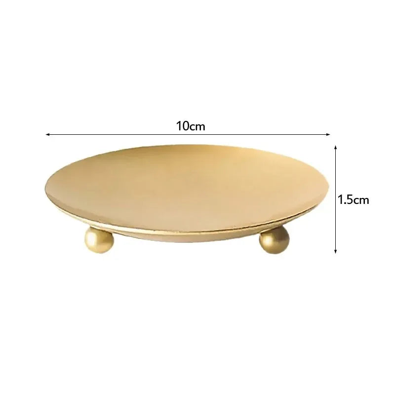 A round, gold-colored iron tray or candle holder with small gold accents.