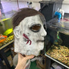 A realistic horror mask resembling Michael Myers, sculpted in gray and black tones.